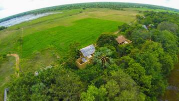 Vista aérea de un paisaje rural con campos verdes, un río y algunas casas dispersas.