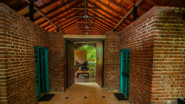 A corridor with brick walls and green doors, leading to a staircase.