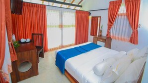 A bedroom with a bed, a desk, and a chair. There are curtains on the windows.