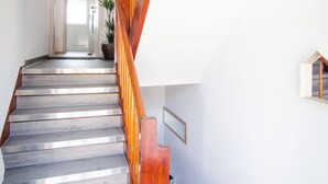 A staircase with wooden railings and a light-colored floor leading to a door. - BB-Apartment (Boeblingen)