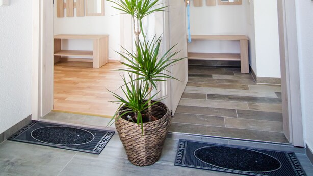 A hallway with two wooden benches, a potted plant, and a welcome mat. - BB-Apartment (Boeblingen)