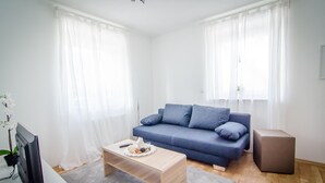 A modern living room with a blue sofa, a wooden coffee table, and a flat-screen TV. - BB-Apartment (Boeblingen)