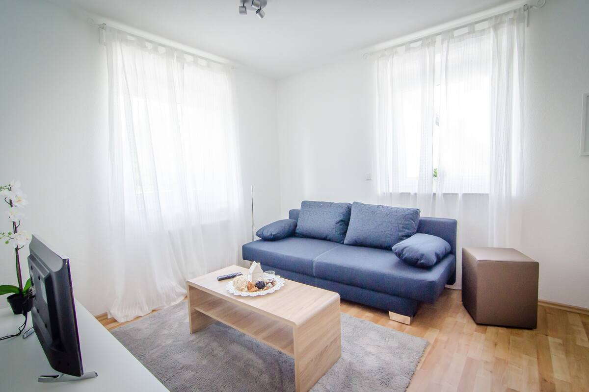 Una sala de estar moderna con un sofá azul, una mesa de centro de madera y un televisor de pantalla plana.