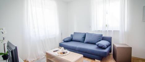 Una sala de estar moderna con un sofá azul, una mesa de centro de madera y un televisor de pantalla plana.