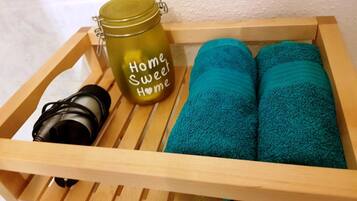 Una bandeja de madera con un tarro verde con la etiqueta "Home Sweet Home", una cámara y dos toallas azul turquesa.
