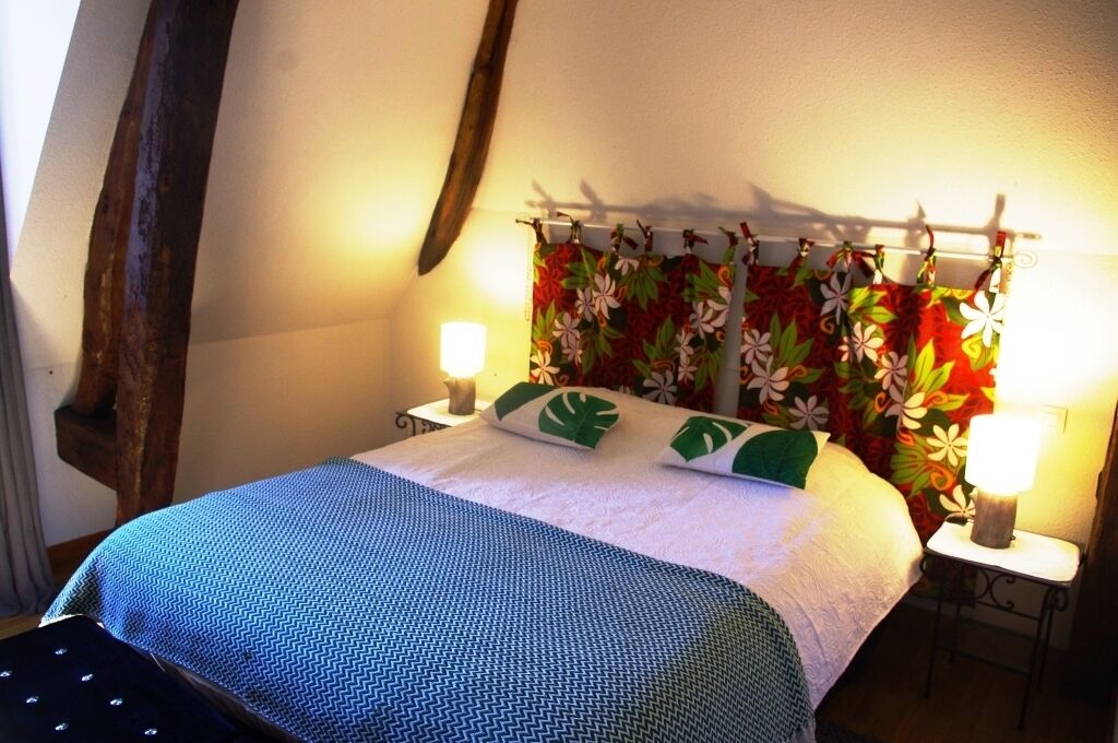 A bed with a patterned bedspread, a floral curtain, and two bedside lamps.