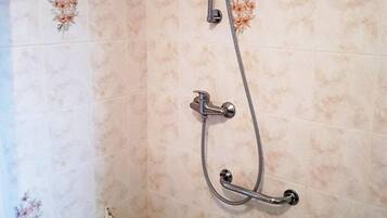 A bathroom with a shower, a white bathtub, and a white shelf unit.