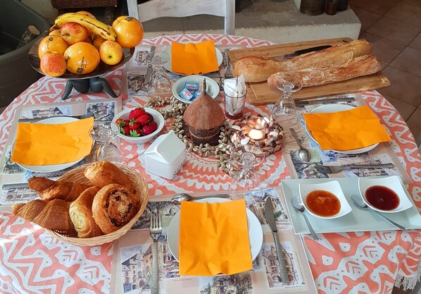 Una mesa servida con frutas, pan y condimentos, ideal para el desayuno o una merienda.