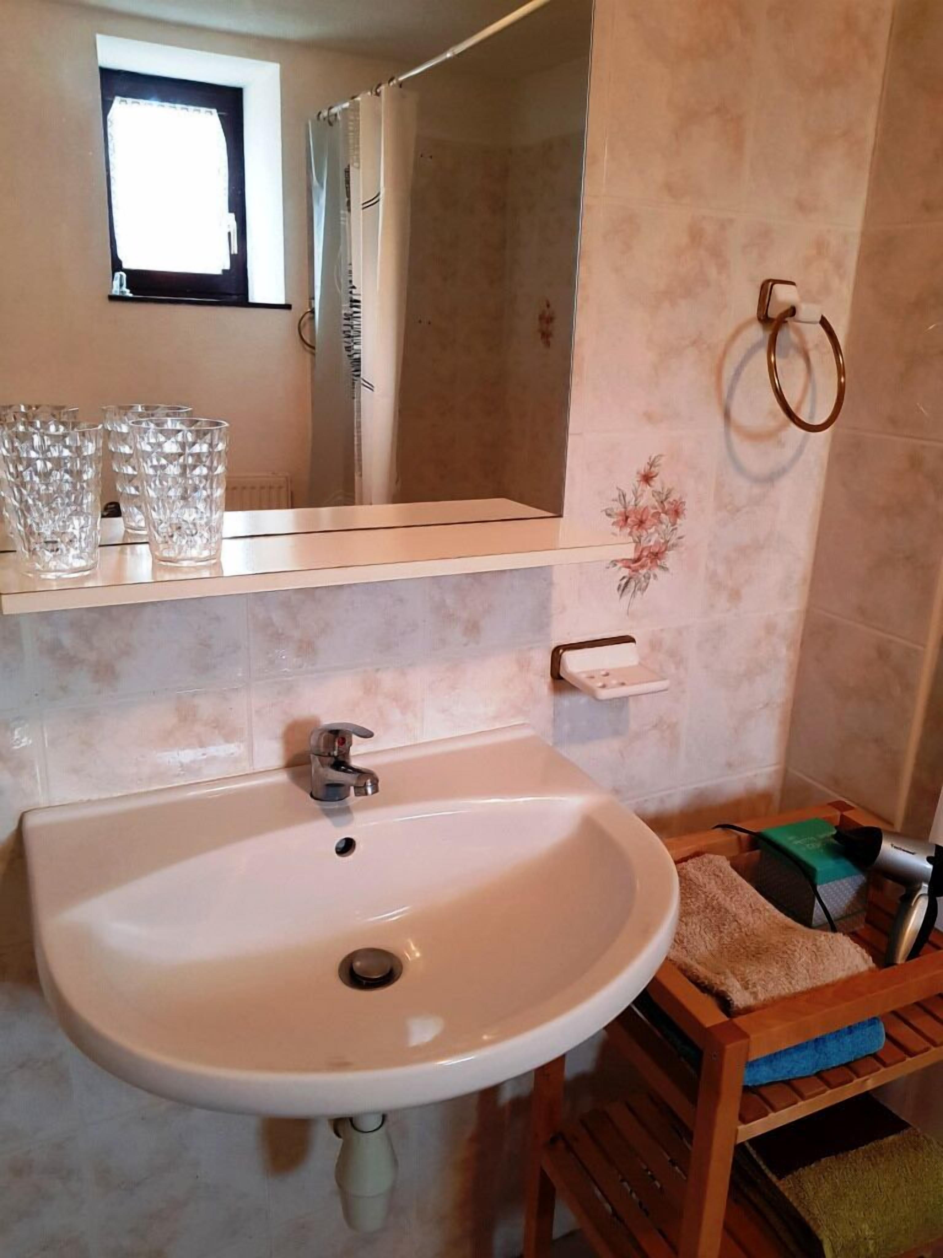 Un baño con lavamanos, espejo y ventana.