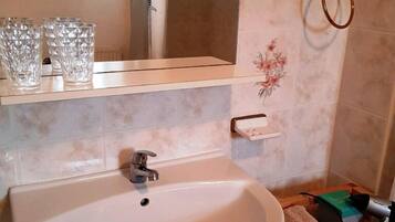 Un baño con lavamanos, espejo y ventana.