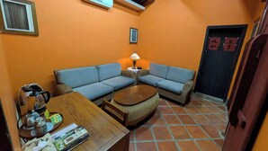 Una habitación acogedora con un sofá, una mesita con una lámpara y suelo de baldosas.