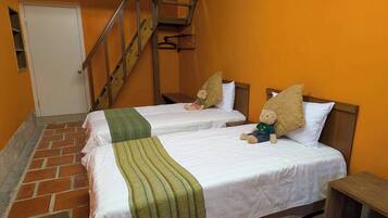 A room with two beds, a wooden staircase, and a door.