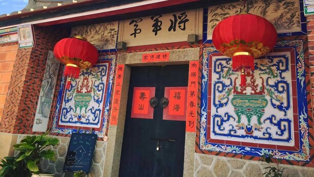 Un edificio tradicional con un vestíbulo de baldosas, faroles rojos y caracteres chinos.