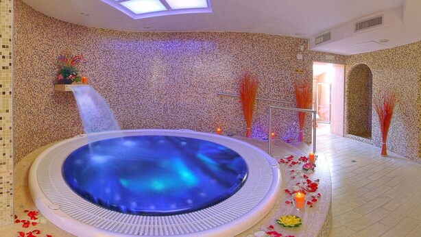 Ein Spa-Bereich mit Whirlpool, Mosaikwänden und einem Oberlicht.