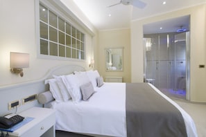 A hotel room with a large bed, a bedside table with a phone, a window, and a bathroom with a glass shower. - Hotel Ristorante Toscana (Alassio)