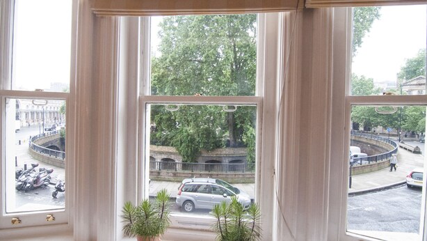 A view from a window with curtains, overlooking a street with parked cars and a roundabout. - CityGate Farringdon (London)