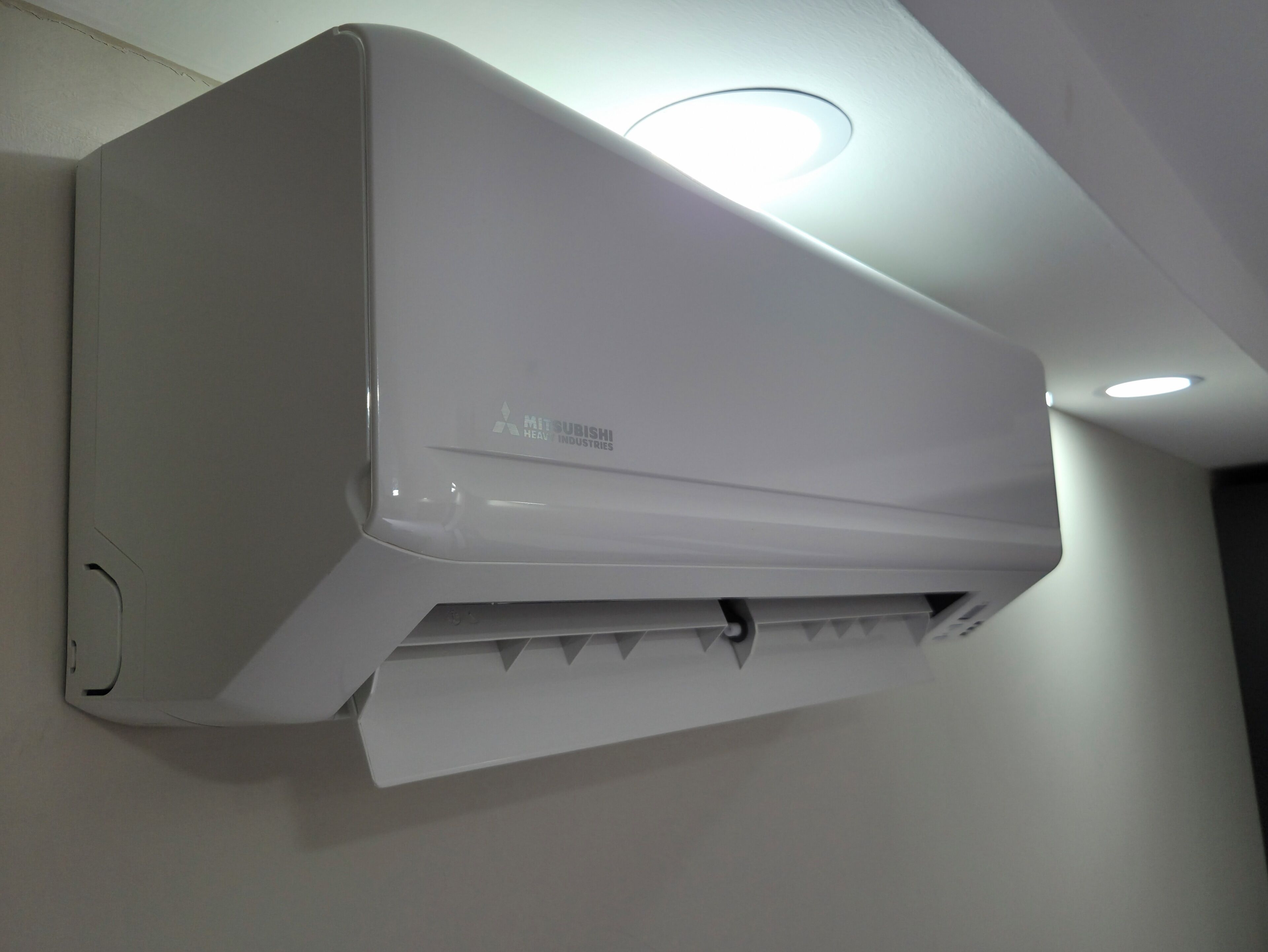 Un climatiseur blanc, fixé au mur, portant le logo Mitsubishi.