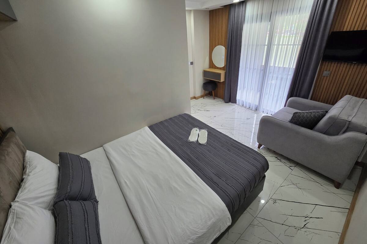 Een hotelkamer met een bed, een bank, een televisie en een raam met gordijnen.
