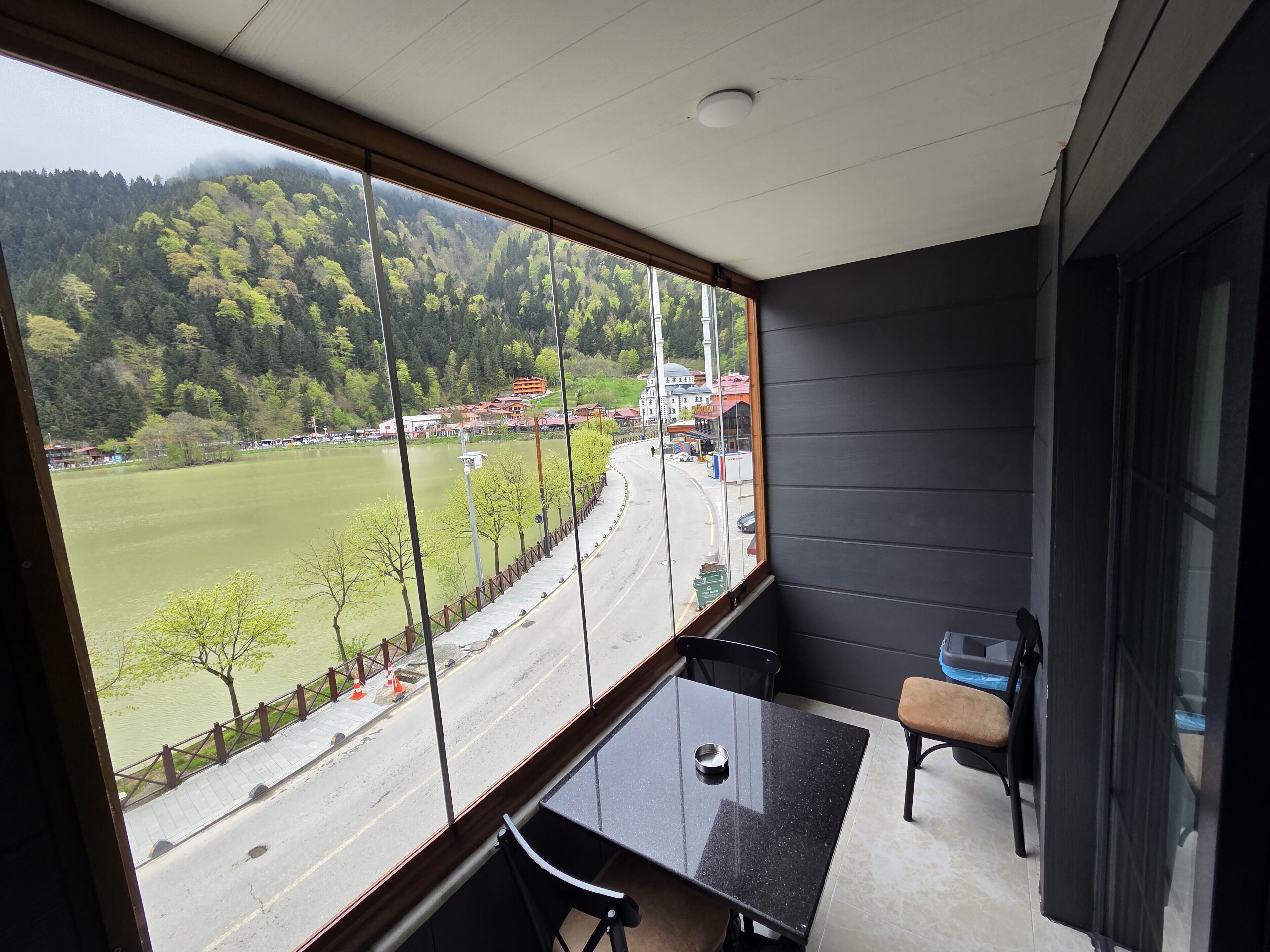 A balcony with a view of a road, trees, and buildings.