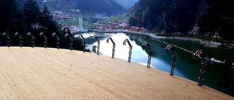 A wooden deck overlooking a river with a town in the valley below.