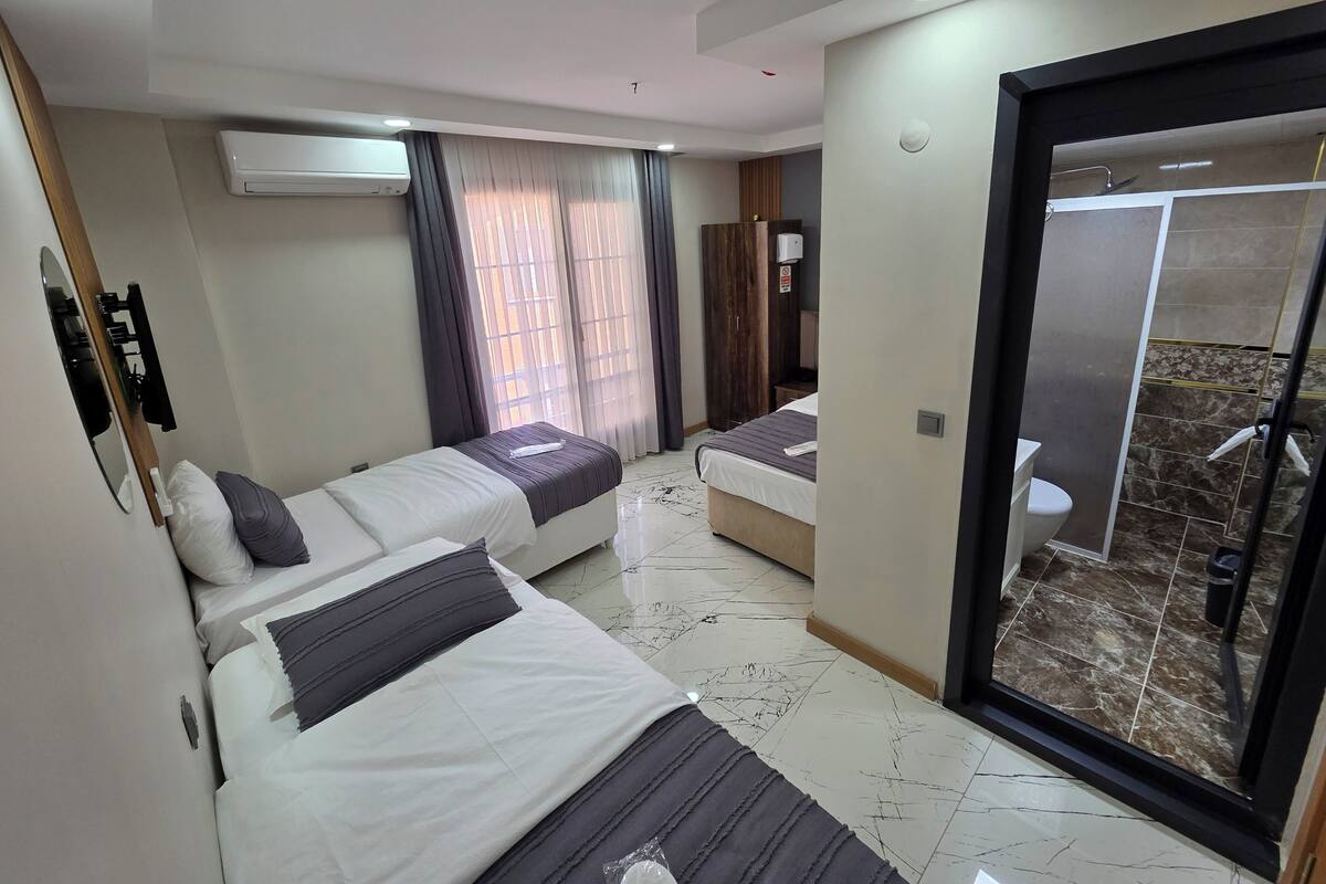 Een hotelkamer met twee bedden, een badkamer en een douche.
