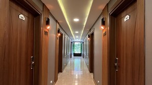 Un pasillo largo y bien iluminado con puertas de madera, cada una identificada con un número.