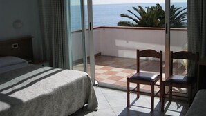 Un dormitorio con cama, una silla y balcón con vistas al mar.
