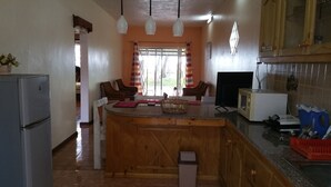 A kitchen with a central island, wooden cabinets, a refrigerator, and a microwave. - Ariambello Vacation (Riambel)