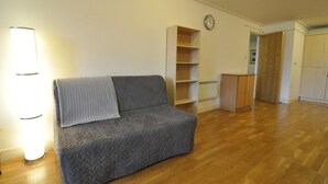 A living room with a grey sofa, a wooden floor, a bookshelf, and a wooden cabinet. - CityGate Old Street (London)