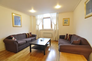 Relax in this stylish living room with two sofas, a coffee table, and a window with white curtains.