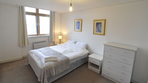 A bedroom with a bed, bedside table, dresser, and two framed pictures on the wall. - CityGate Old Street (London)