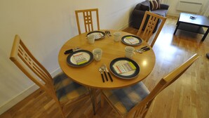 A dining table set with plates, cutlery, and cups, surrounded by chairs with plaid cushions. - CityGate Old Street (London)