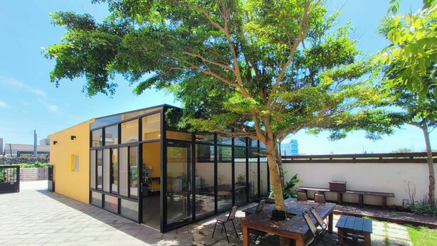A modern outdoor seating area with a glass enclosure, a wooden table, and a bench. - MouMoon (Magong)