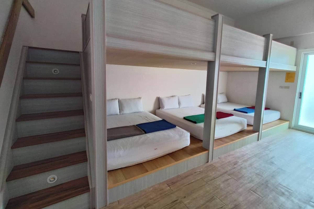 A bunk bed room with a wooden staircase and a door.