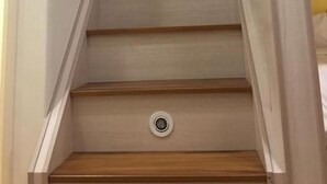 Un escalier en bois, doté d’une rampe et d’un interrupteur sur le mur.