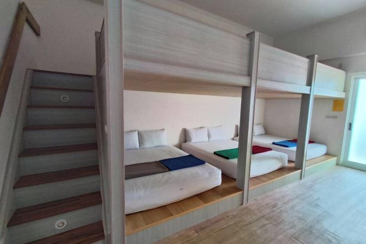 A room with bunk beds, a staircase, and a door leading to another area.