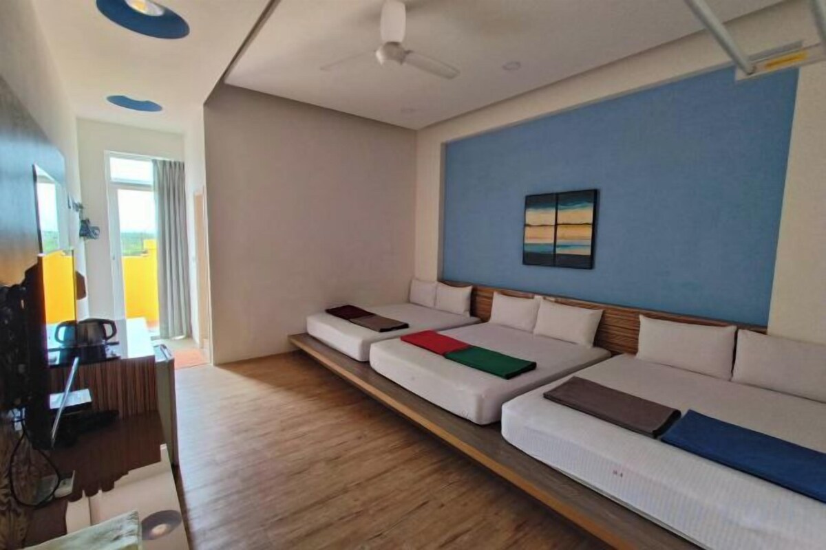 A room with a long sofa, a desk with a chair, and a bed with a headboard.