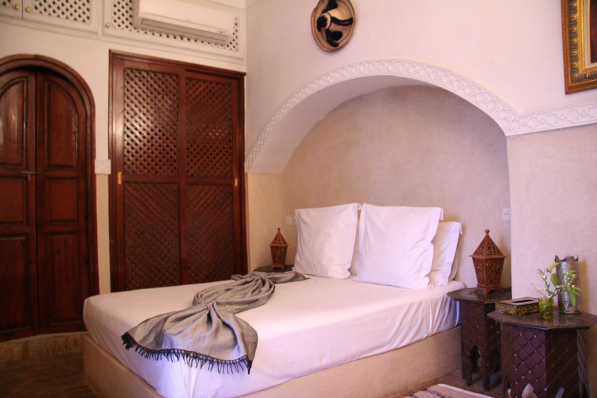 A bedroom with a bed, wooden wardrobe, and decorative lanterns.