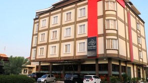 A multi-story hotel with a prominent red accent on the corner, featuring a sign for the Grand Dian Boutique Hotel. - Grand Dian Boutique Hotel (North Cirebon)