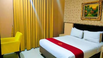 A hotel room with a bed, a yellow chair, and a painting on the wall.