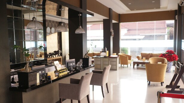 A modern hotel lobby with a reception desk, seating area, and large windows. - Grand Dian Boutique Hotel (North Cirebon)