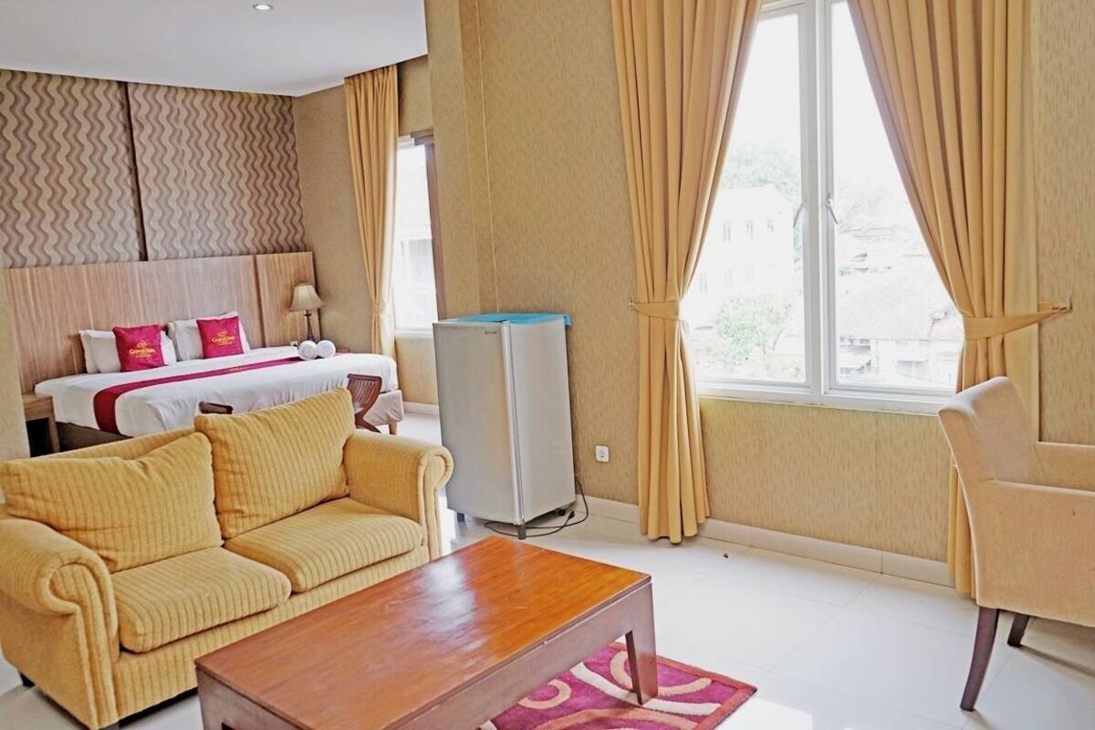A hotel room with a bed, a sofa, a coffee table, and a TV.