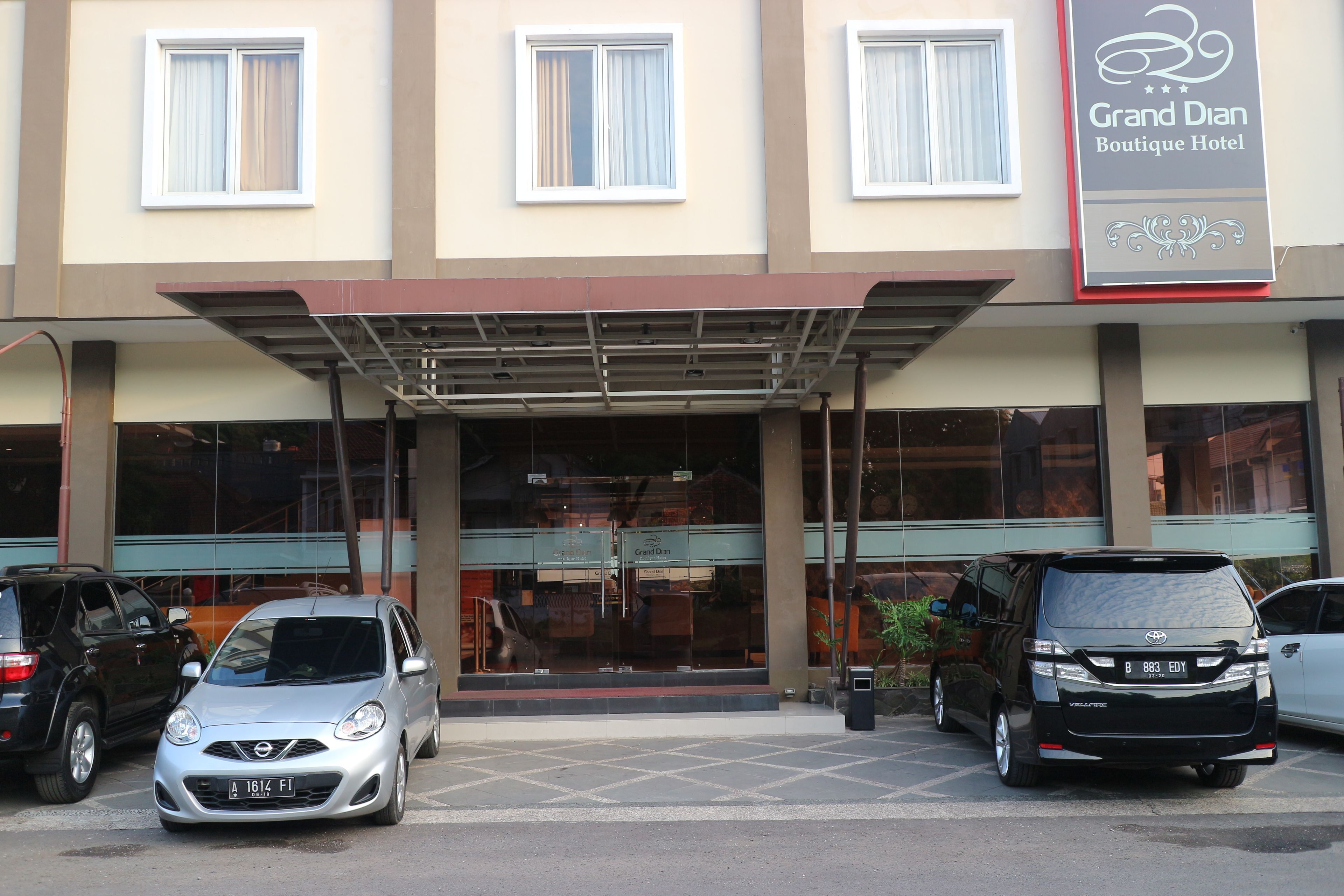 A Grand Dian Boutique Hotel with a covered entrance, multiple cars parked in front, and a clear view of the building's facade.