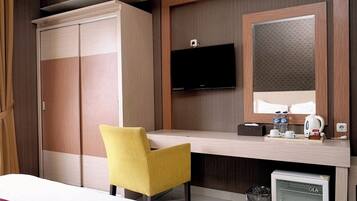 Une chambre d’hôtel comprenant un lit, un bureau avec une chaise, une télévision, un miroir, un réfrigérateur de la marque GE et une armoire.
