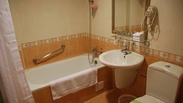 Un baño con bañera, lavamanos e inodoro.