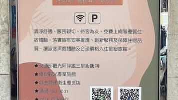 A hotel sign with a logo, QR codes, and text describing amenities and services.