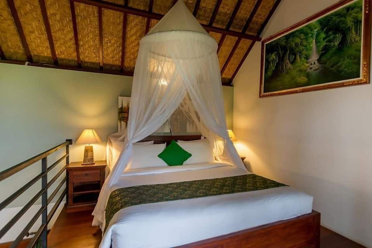 A bedroom with a bed under a canopy, a nightstand with a lamp, and a painting on the wall.