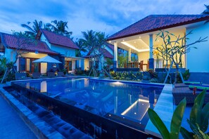 Un resort moderno con piscina, mobiliario exterior y plantas tropicales.