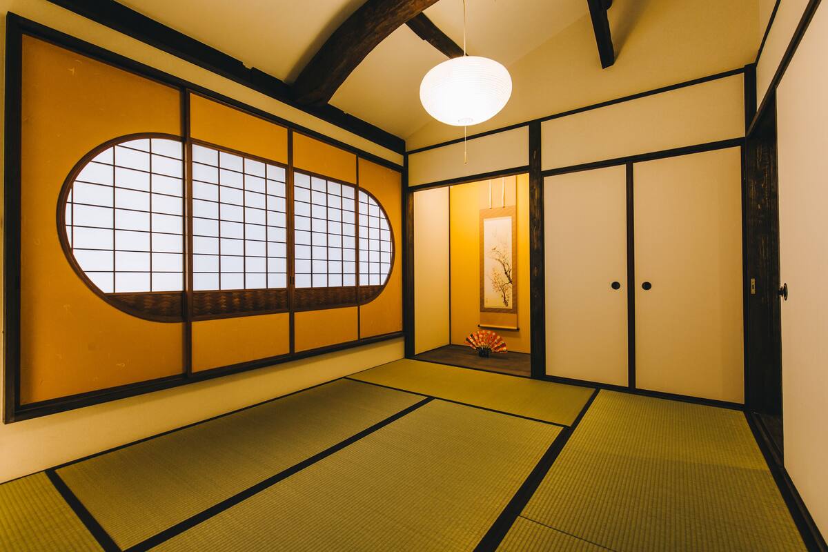 Una habitación japonesa tradicional con suelo de tatami, puertas correderas y un mamparo de papel shoji.