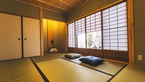 Une pièce de style japonais traditionnel, avec un sol recouvert de tatamis, des portes coulissantes et une vue à travers des panneaux shoji.